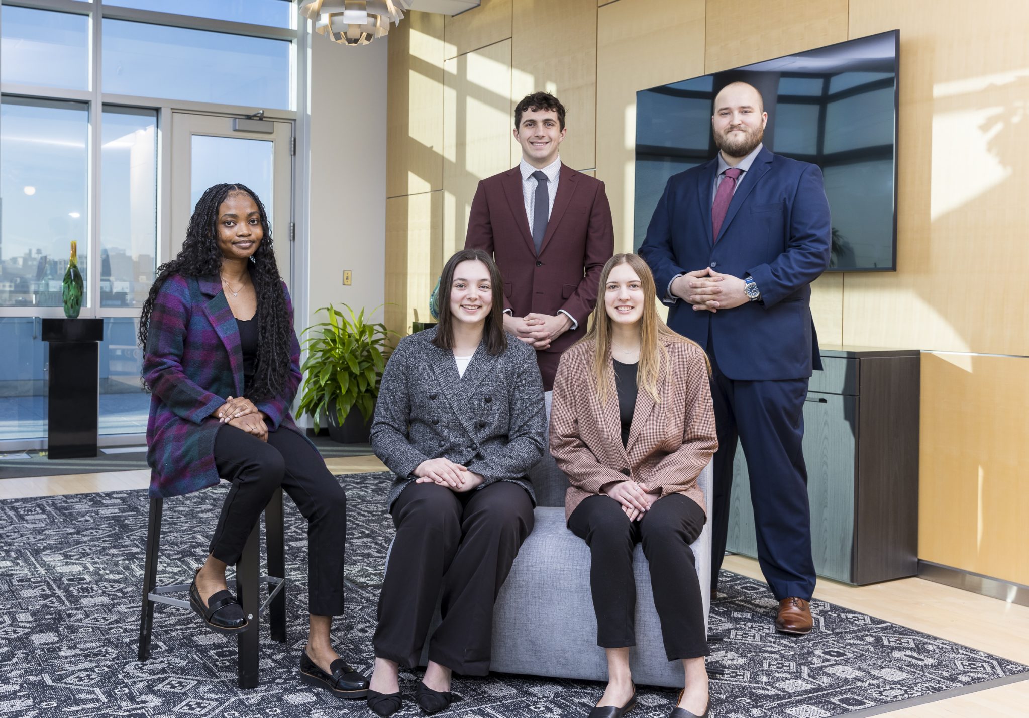 Five professionally dressed students pose together in a modern office setting, representing the Gustavus Innovation Scholars program
