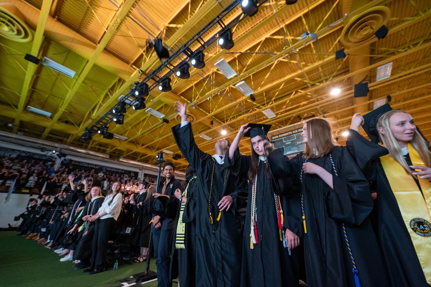 College students throw their hats up at a Commencement ceremony. 