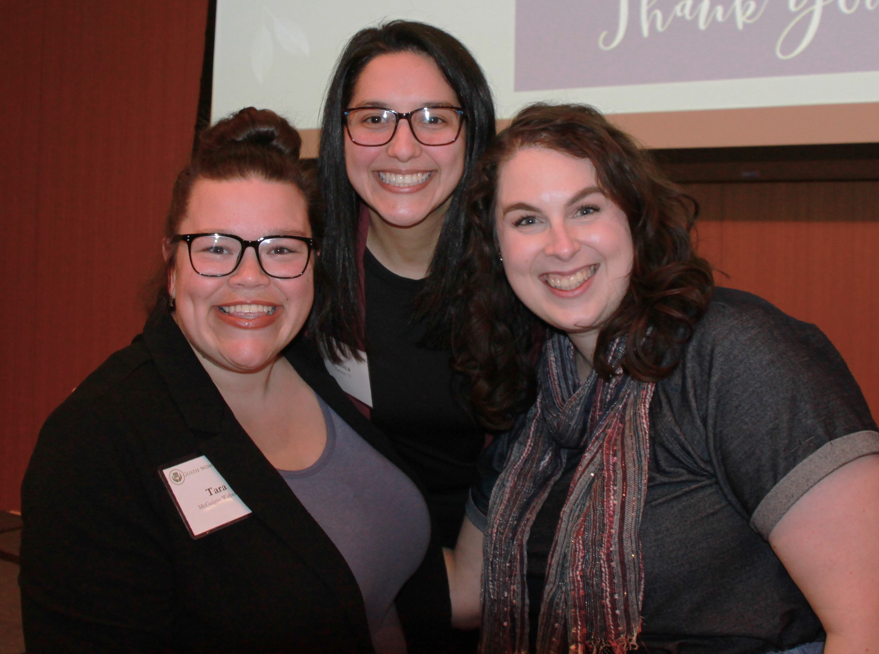 Three women smile for the camera at a fundraising event. 