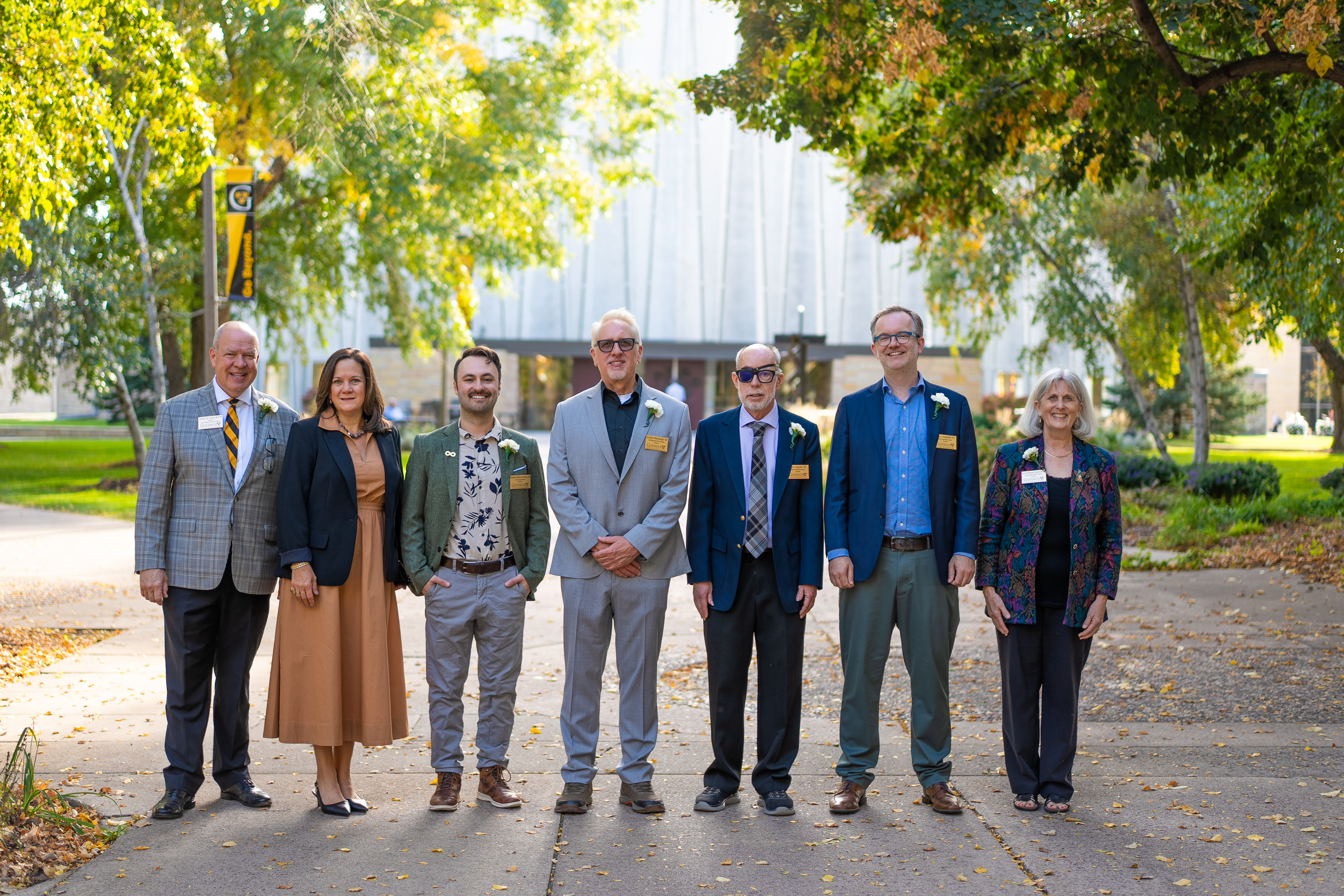 Group of seven alumni standing in front of Christ Chapel