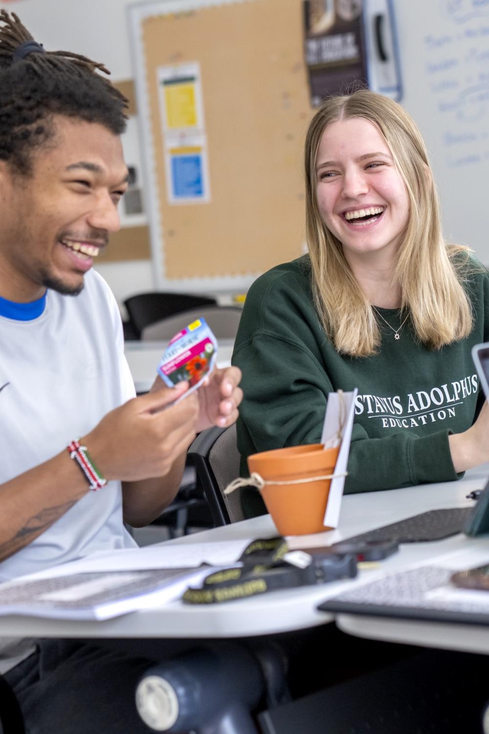 Two students laugh with each other. 