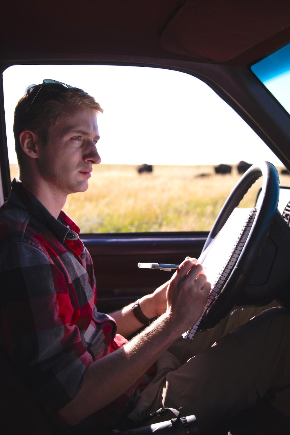 Student writing on a clipboard about observing bison