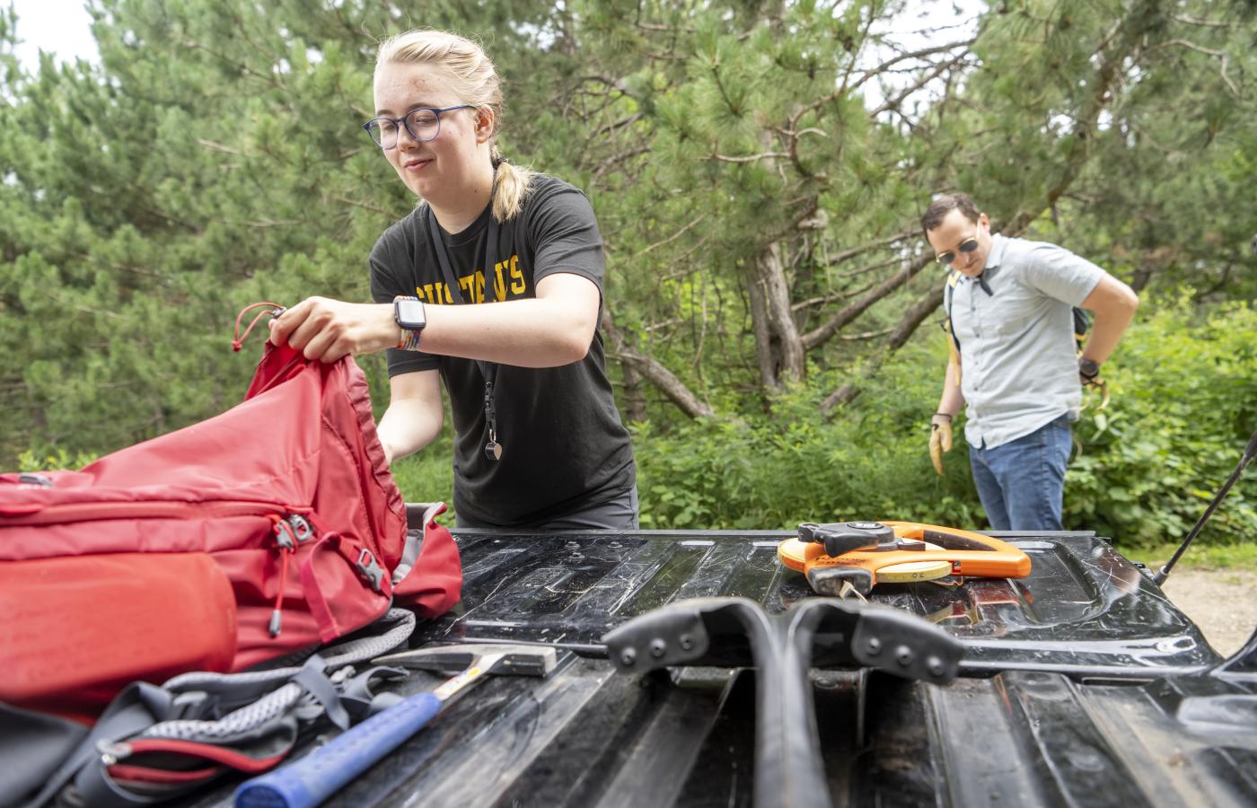 A student and her professor prepare their backpacks for a hike. 