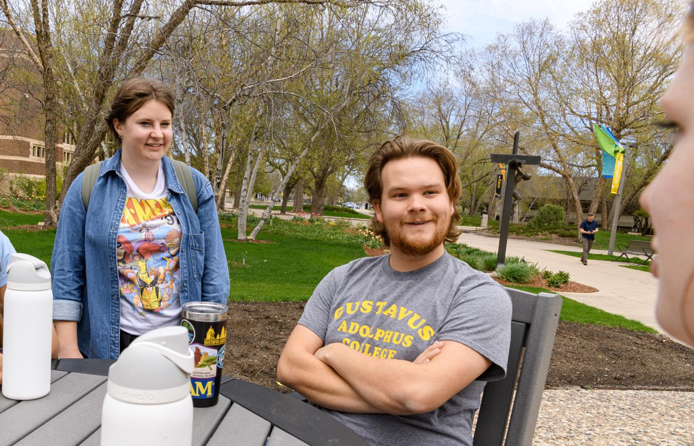 Two students listen while hanging out outside. 