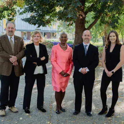Group photo of five Alumni Award winners standing outside on a fall day