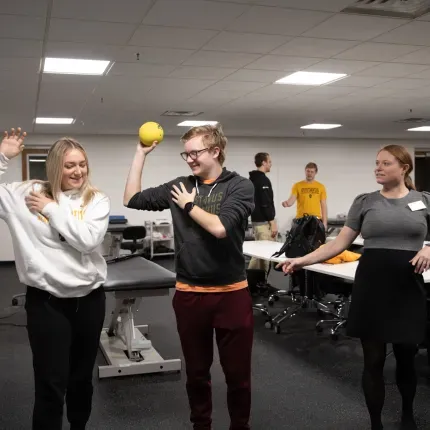 A college student demonstrates with a ball how a shoulder works. 