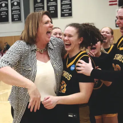 A women's basketball coach celebrates with her team after a big, emotional win. 