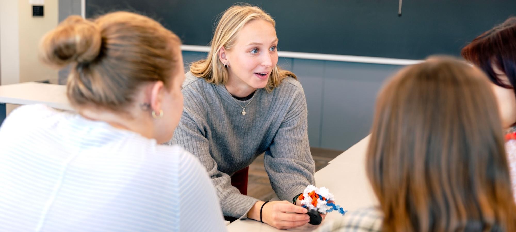A college student teaches with a science model. 