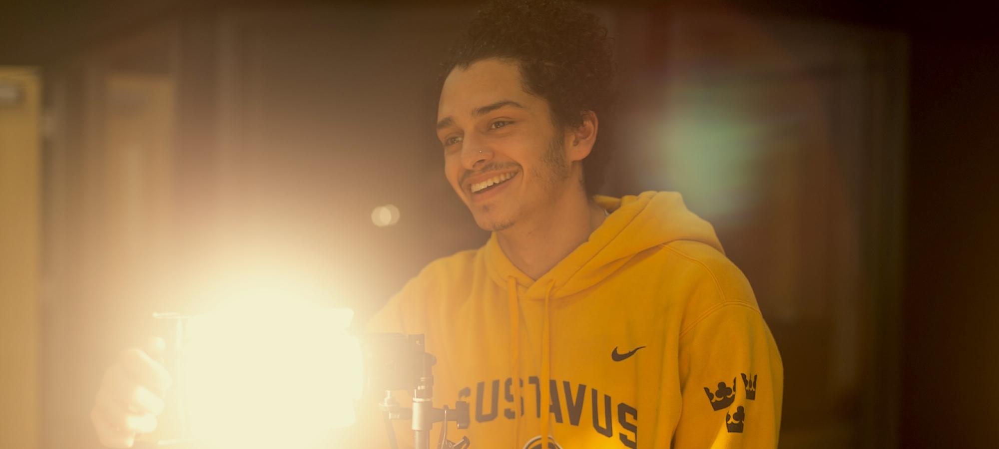 A Gustavus Adolphus college student adjust lighting in a studio. 