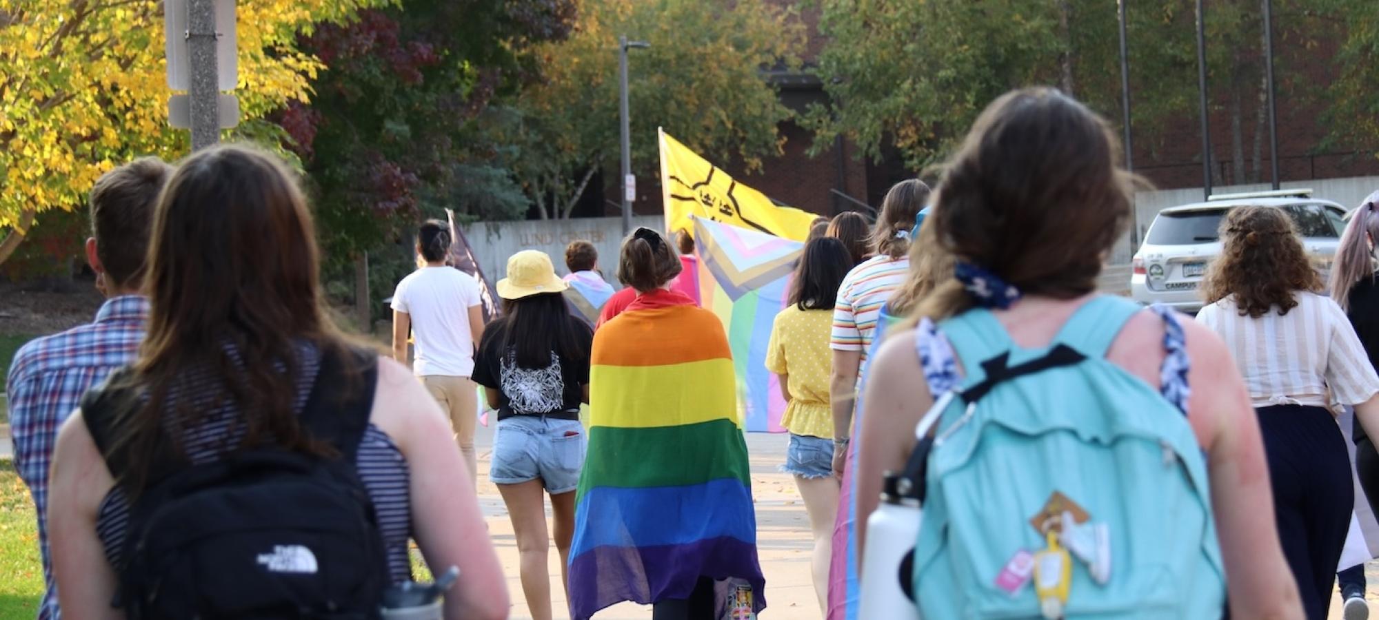 Students at a parade with different gender-related flags. 