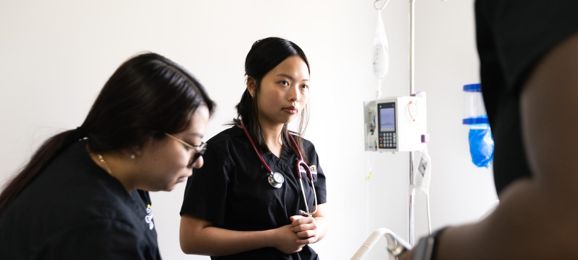 A nursing student listens to an instructor. 