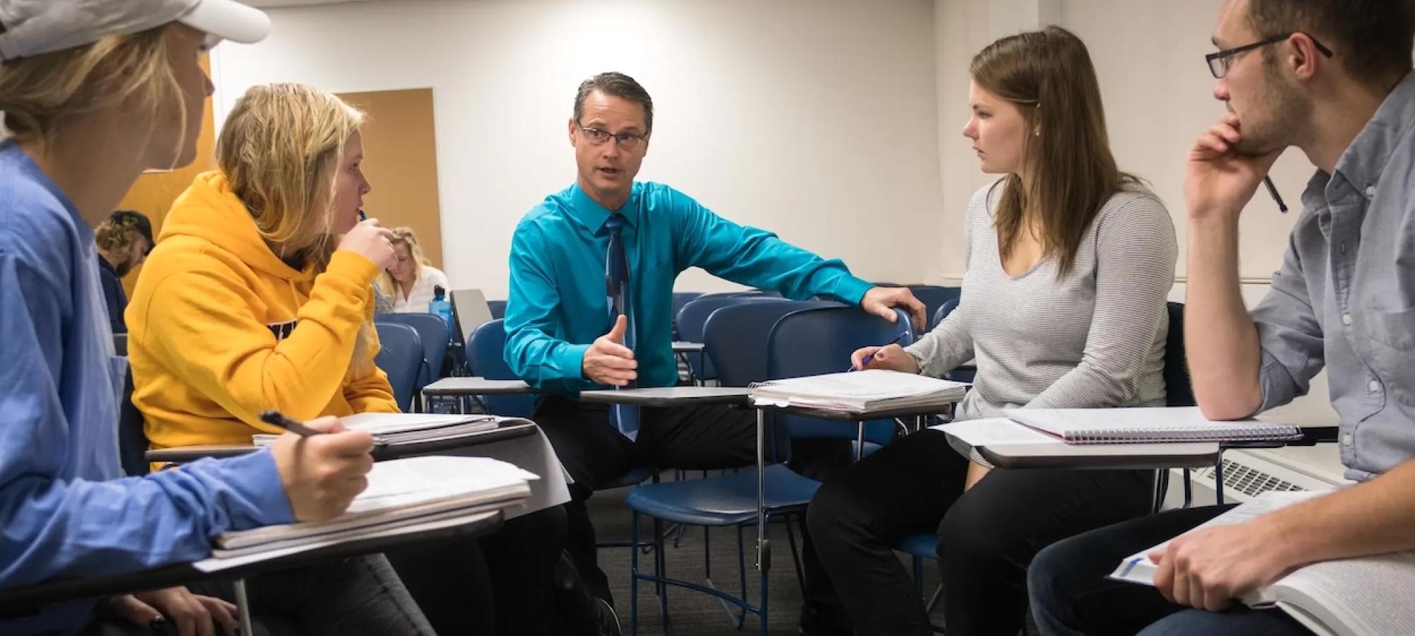 A Gustavus Adolphus College professor discusses public health with four students. 
