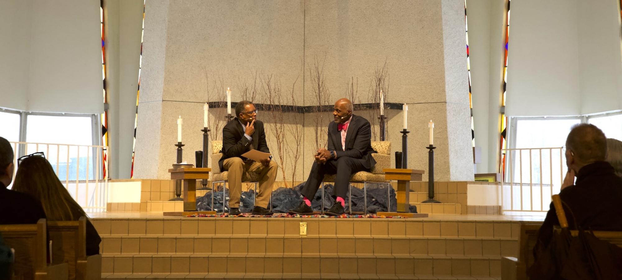 Two men discuss intently in a church.