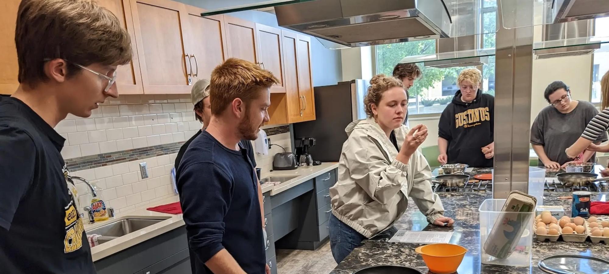 Students consider food in a kitchen. 
