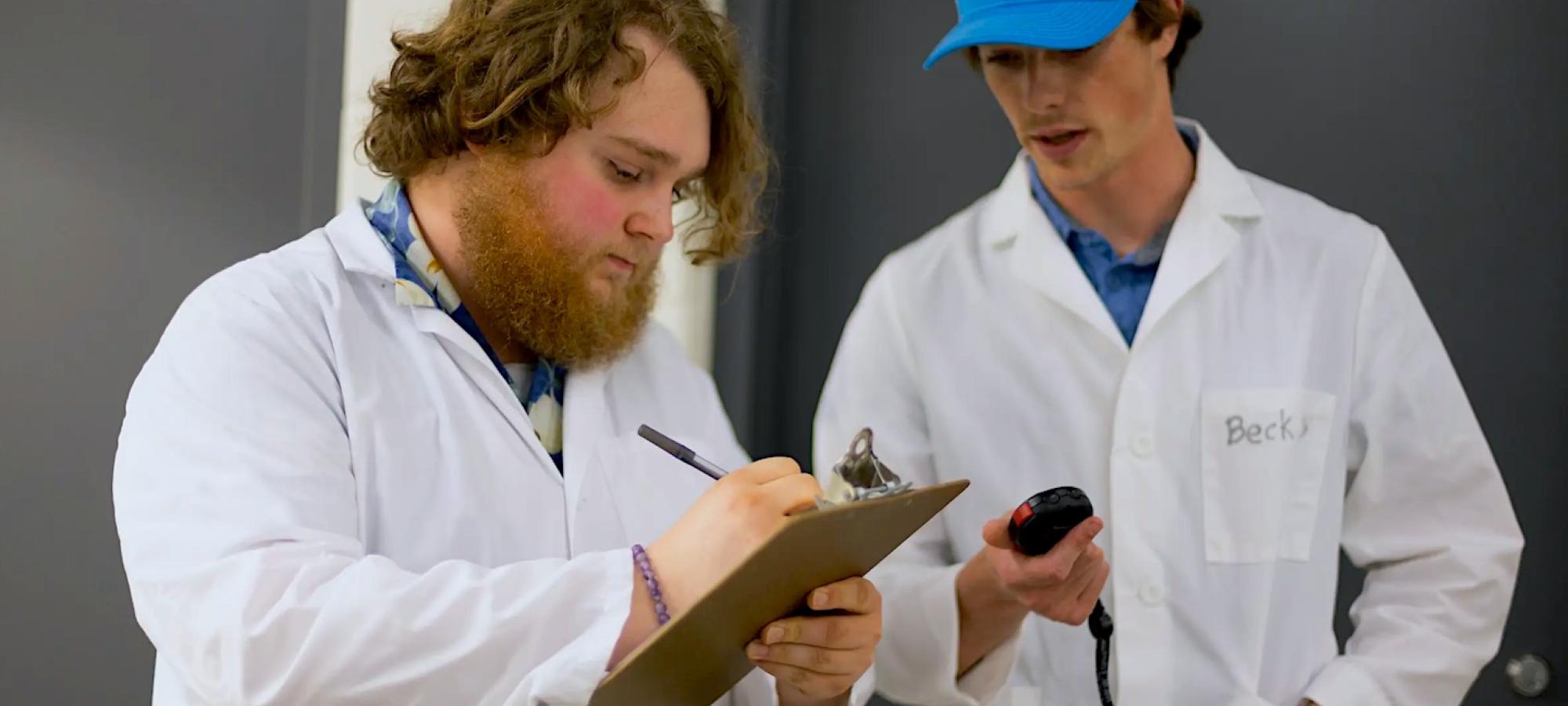 Gustavus Adolphus College pyschological science students in lab coats make notes.