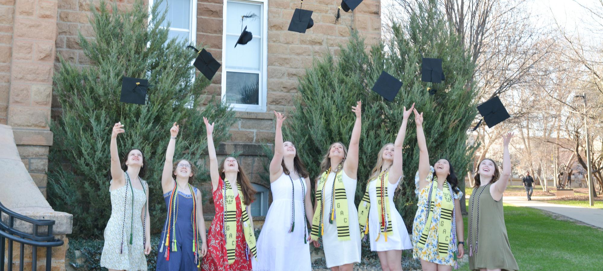 Women tossing hats at old main