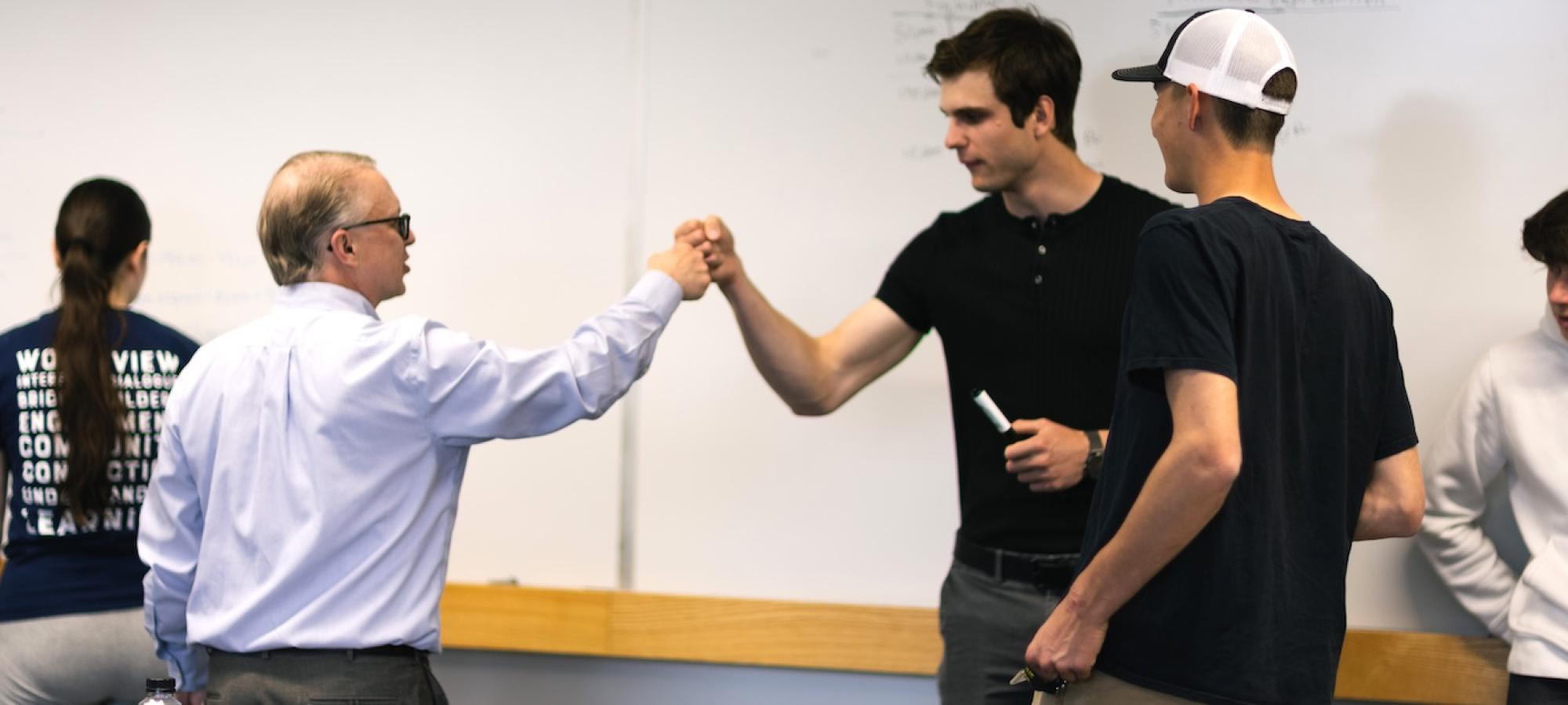 A college student fist-bumps his professor.