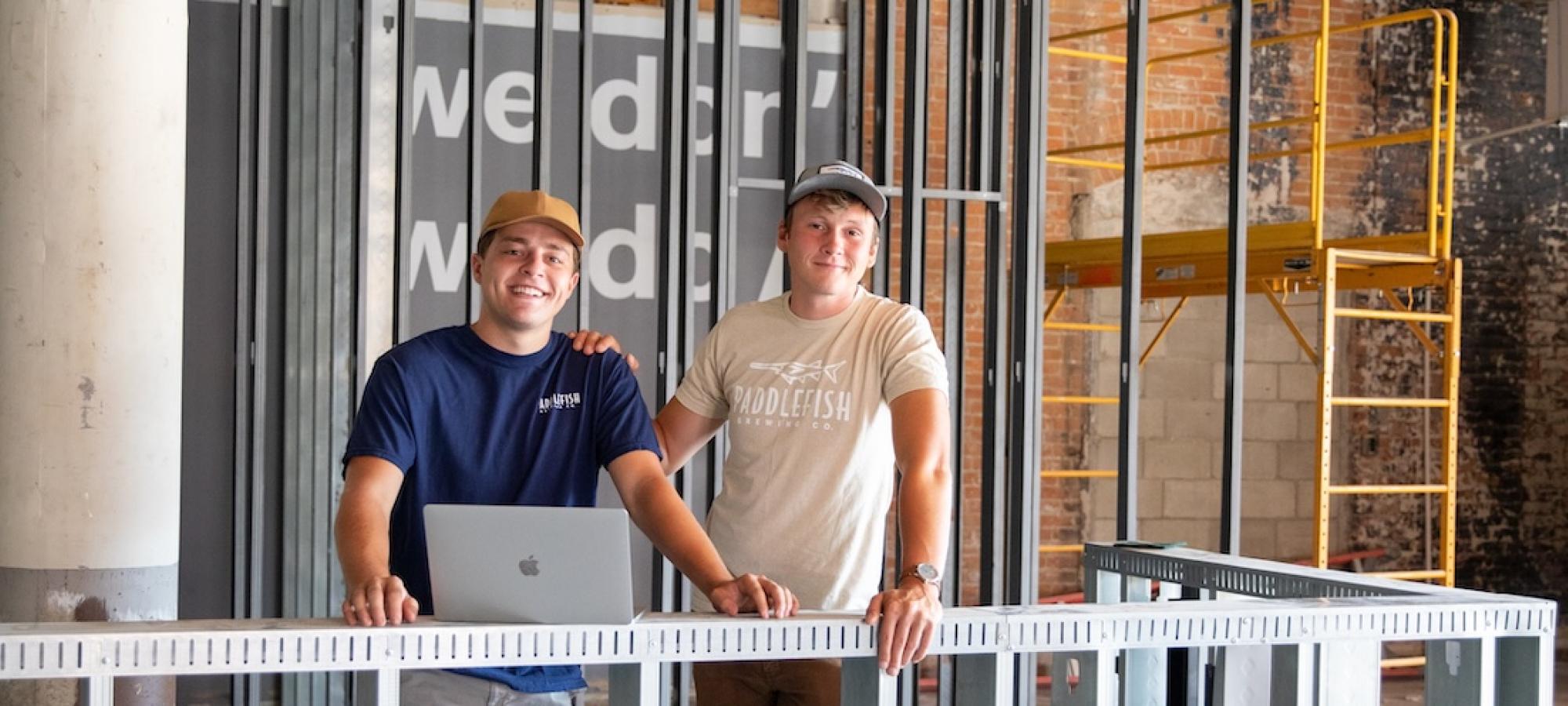 Two young men in front of their new brewery. 