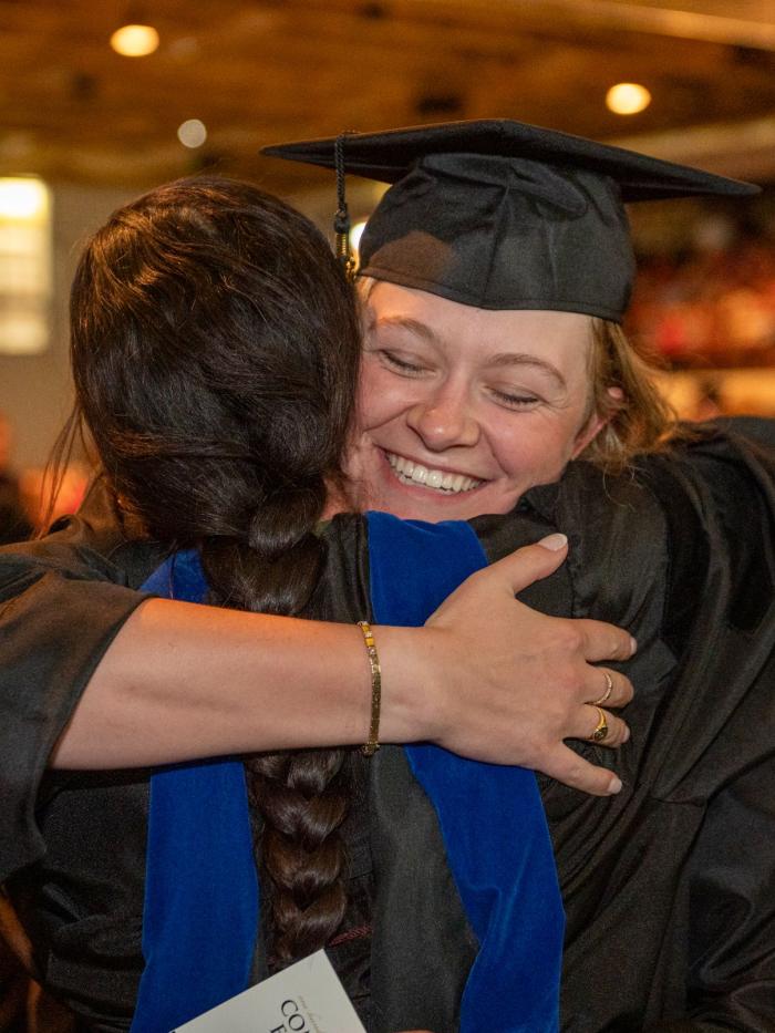 Student and faculty hugging at Commencement