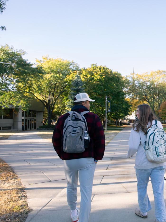 3 students on Eckman Mall and Carlson Administration Building