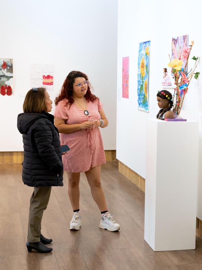Two women examine art in a gallery at Gustavus Adolphus College. 