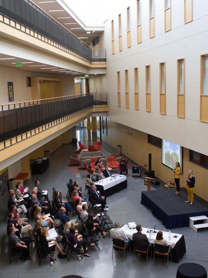 People assembled in an academic hall to watch students present. 