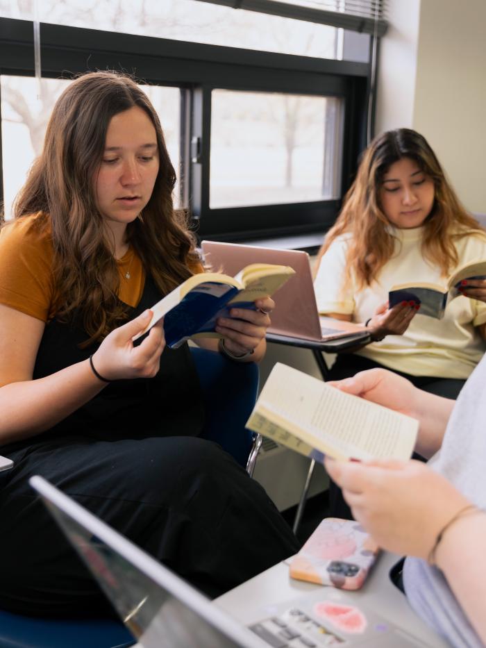 A woman reads a book in college. 