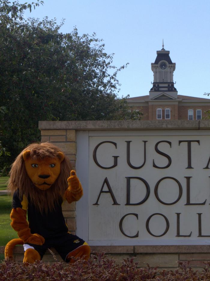 Gus at Gustavus sign with thumbs up