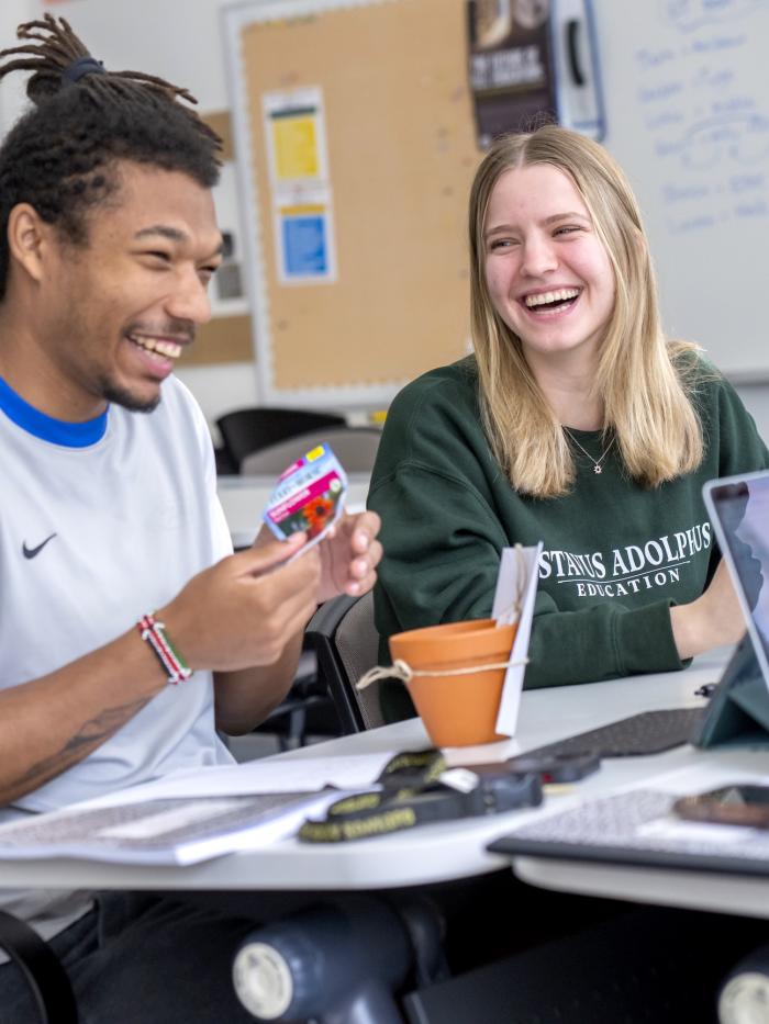 Two students laugh with each other. 