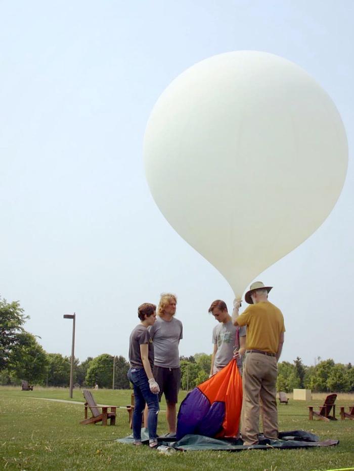 Students and a professor prepare to launch a weather balloon. 