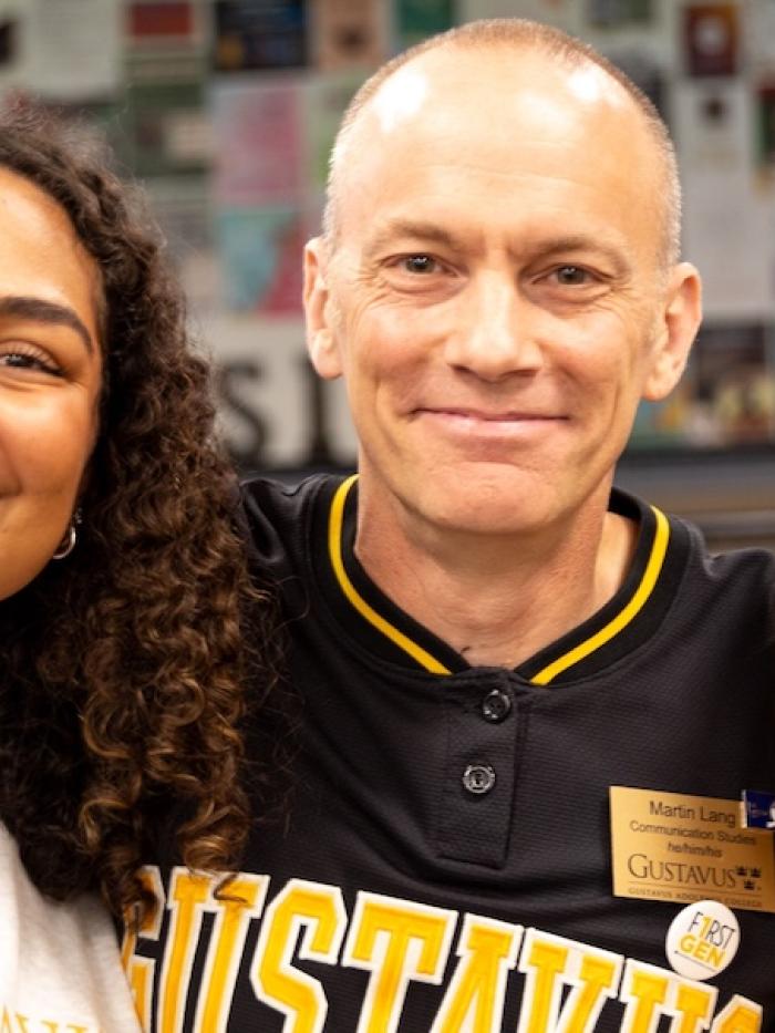 A man and two students smile at the camera. 