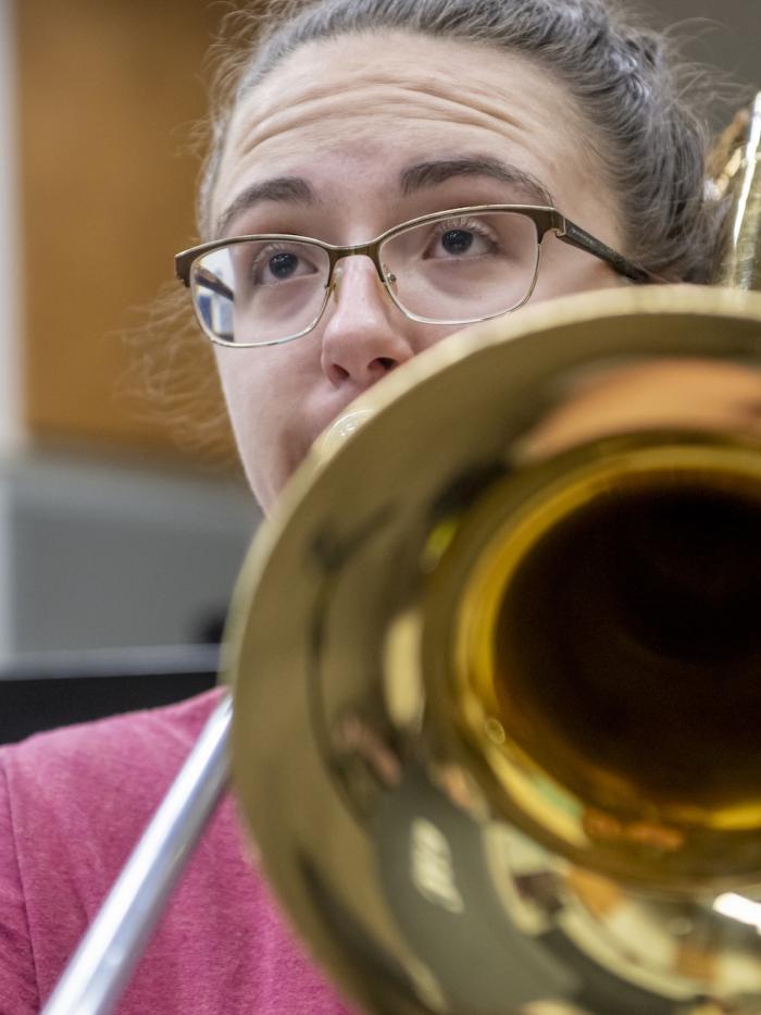 A student looks up while playing the trombone. 