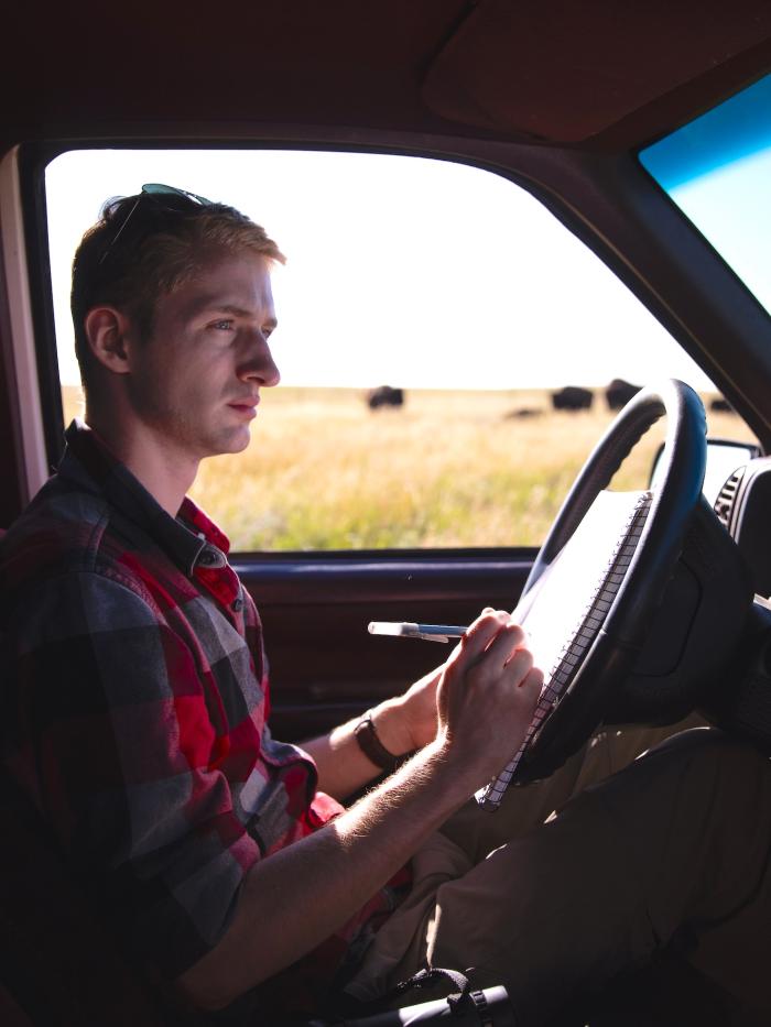Student writing on a clipboard about observing bison