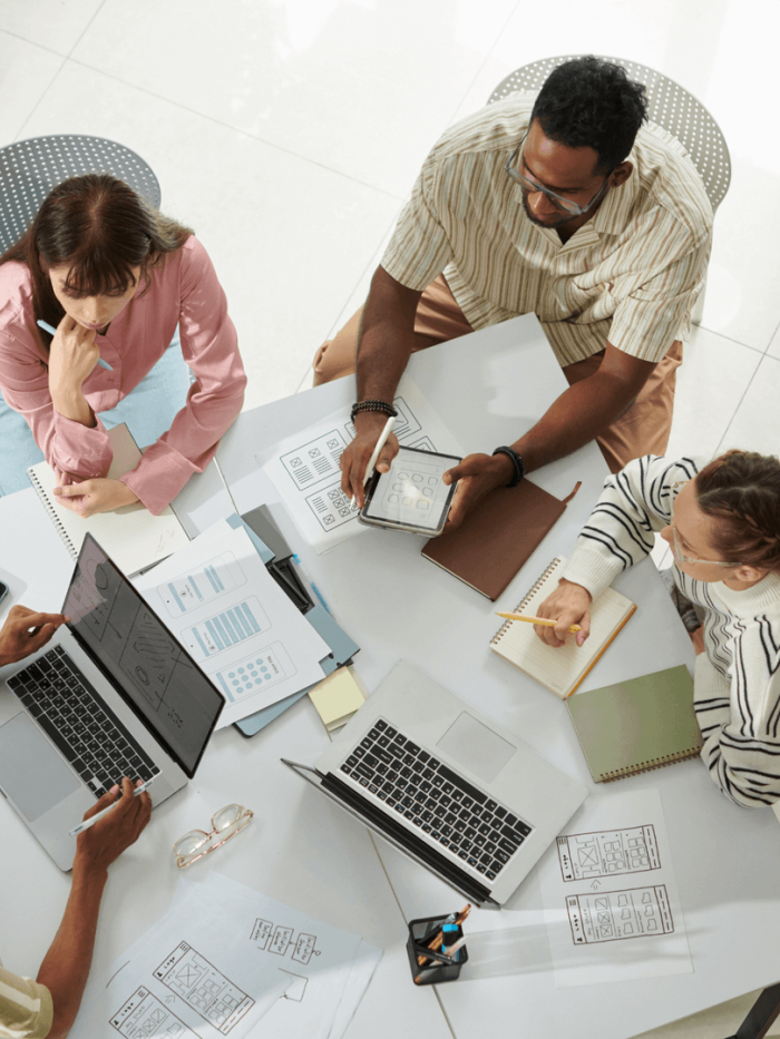 Young adults working at table together with laptops