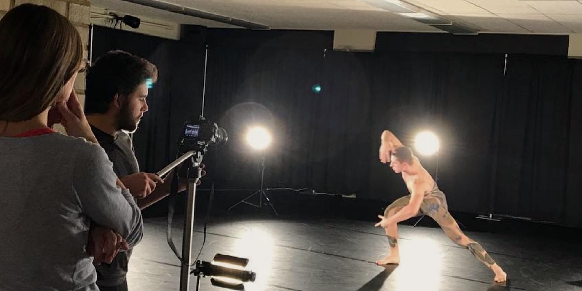 A Gustavus student videographer films a dancer with a spotlight. 
